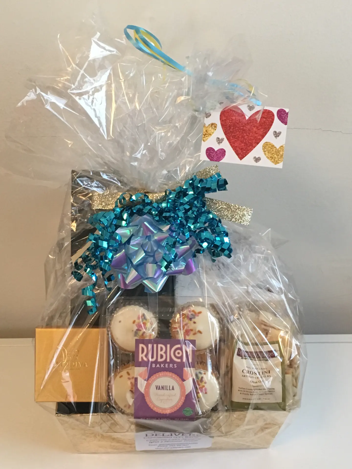 Finished Diana Delivers basket wrapped in cellophane with a teal bow and a heart gift tag